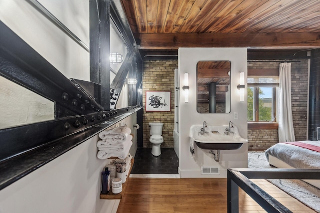 bathroom with toilet, wood-type flooring, brick wall, and wooden ceiling