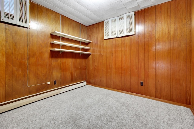 carpeted spare room featuring wood walls and a baseboard radiator