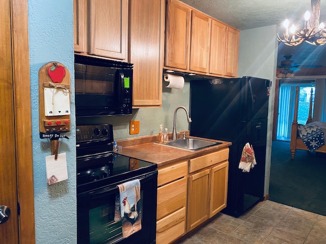 kitchen featuring black appliances, a sink, a textured wall, a chandelier, and a textured ceiling