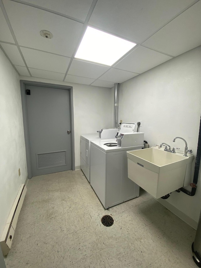 washroom with baseboard heating, washing machine and dryer, a sink, and light floors