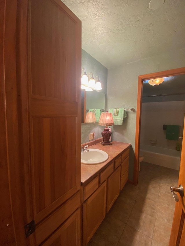 bathroom featuring vanity, a bathtub, tile patterned flooring, toilet, and a textured ceiling