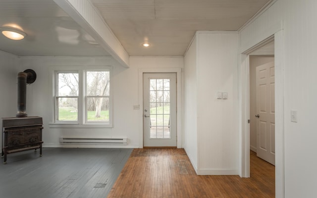 doorway to outside with hardwood / wood-style flooring, a wood stove, and a baseboard heating unit