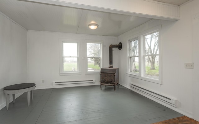 living area featuring dark wood-type flooring, a wood stove, baseboard heating, and plenty of natural light