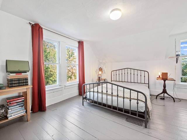 bedroom featuring hardwood / wood-style flooring, lofted ceiling, and multiple windows