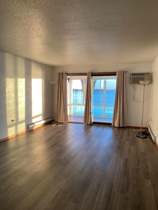 unfurnished living room with baseboards, dark wood-type flooring, a wall mounted air conditioner, baseboard heating, and a textured ceiling