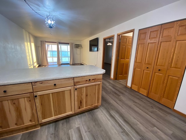 kitchen with light countertops, dark wood-type flooring, a peninsula, and an AC wall unit