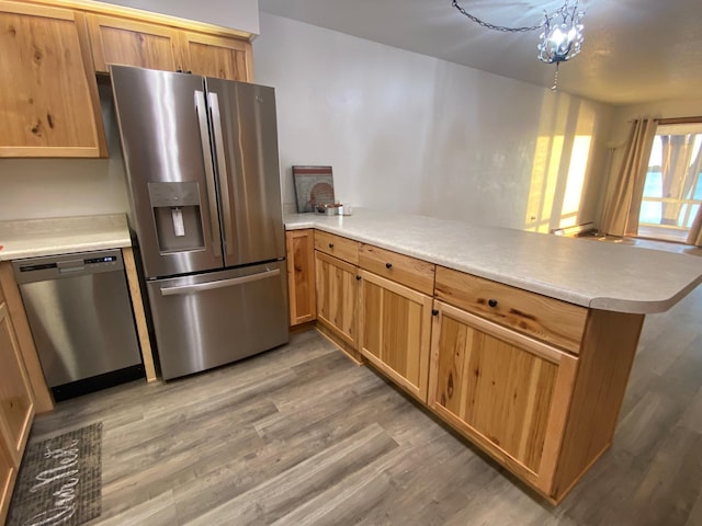 kitchen featuring appliances with stainless steel finishes, light countertops, a peninsula, and light wood finished floors