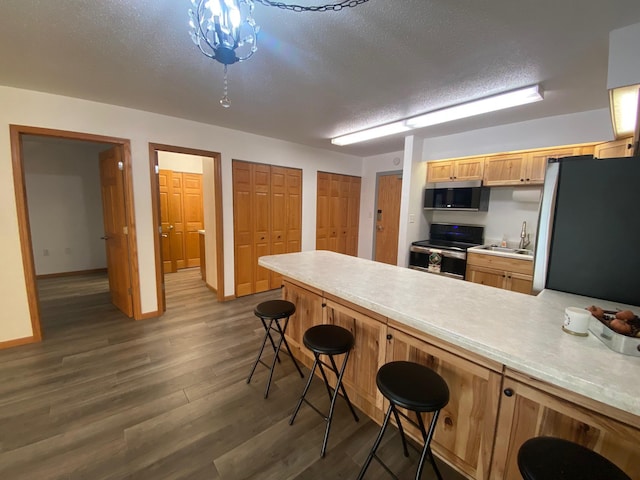 kitchen featuring dark wood-style flooring, stainless steel appliances, light countertops, a textured ceiling, and a peninsula