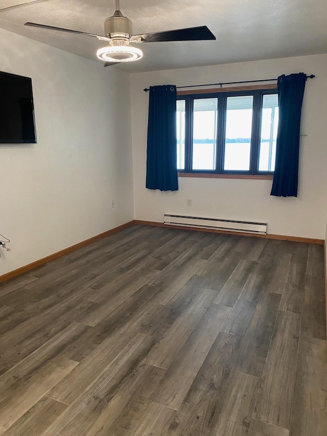 spare room featuring dark wood-style floors, baseboards, and baseboard heating