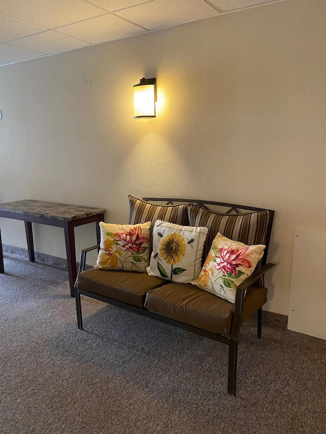 carpeted living area with a drop ceiling