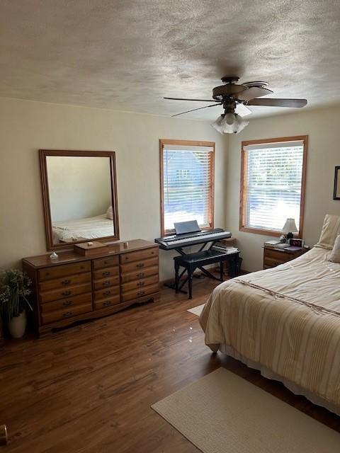 bedroom with dark hardwood / wood-style floors, a textured ceiling, and ceiling fan