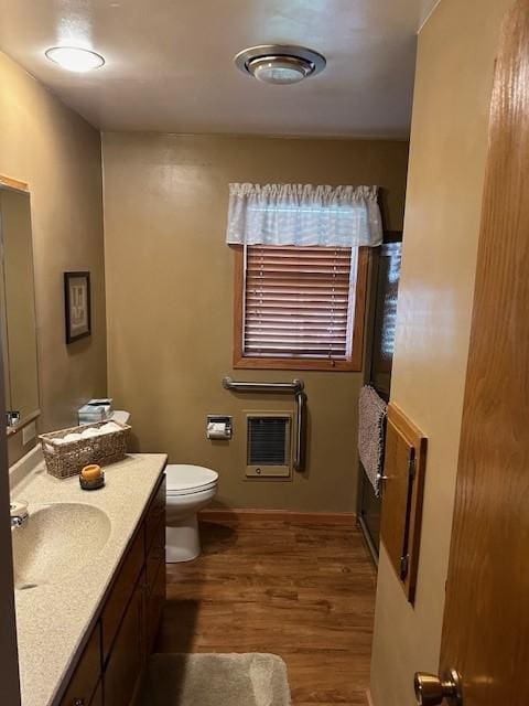 bathroom with toilet, hardwood / wood-style flooring, vanity, and heating unit