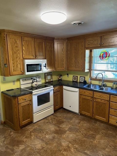 kitchen with a textured ceiling, sink, and white appliances