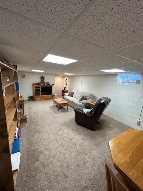 living room featuring a drop ceiling and carpet floors