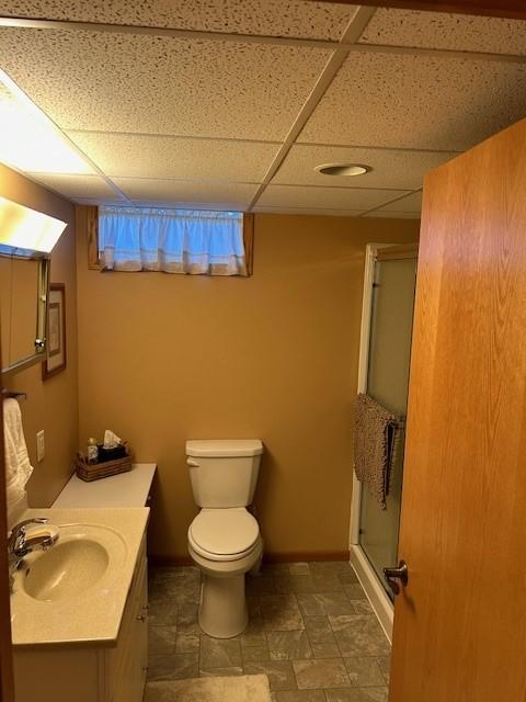 bathroom featuring vanity, a paneled ceiling, toilet, and an enclosed shower