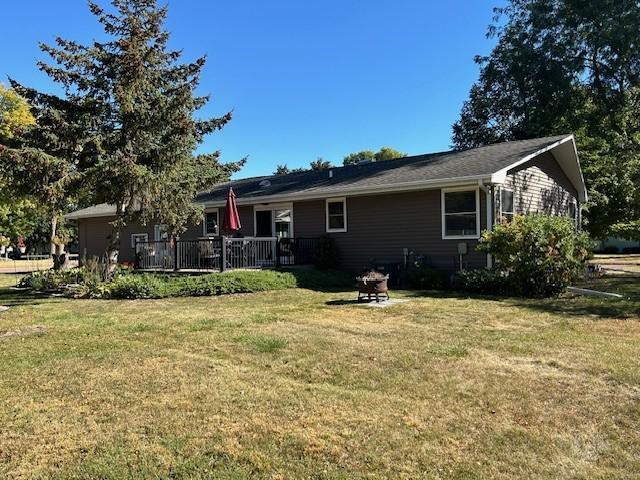 back of property with a wooden deck and a lawn