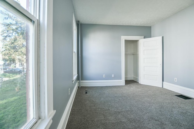 unfurnished bedroom featuring dark carpet and a closet