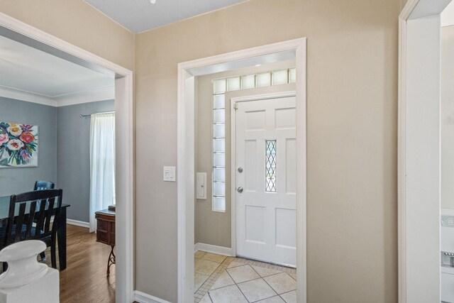 entryway with light wood-type flooring and crown molding