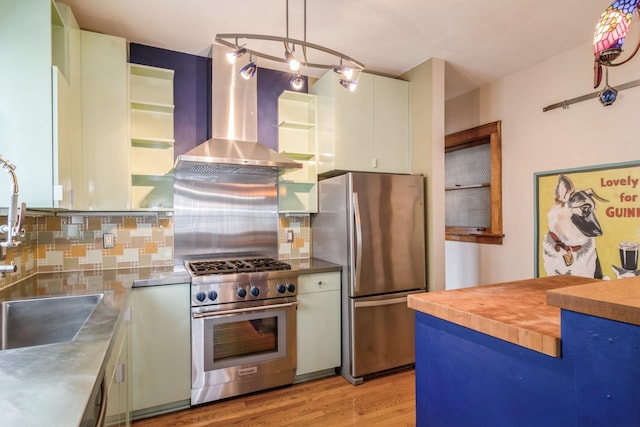 kitchen with hanging light fixtures, wall chimney exhaust hood, decorative backsplash, appliances with stainless steel finishes, and stainless steel counters