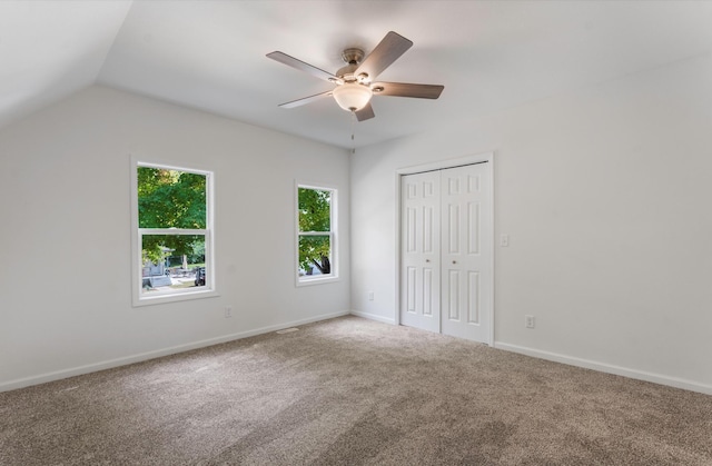 unfurnished bedroom with ceiling fan, carpet, a closet, and lofted ceiling