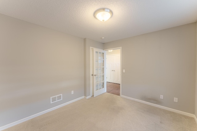 empty room featuring light carpet and a textured ceiling