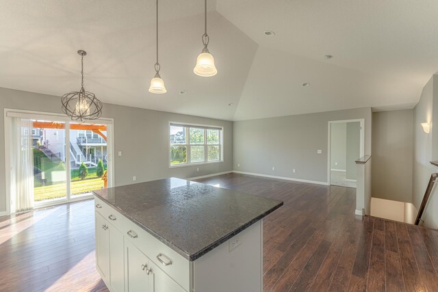 kitchen featuring lofted ceiling, white cabinetry, dark stone countertops, and dark wood-type flooring