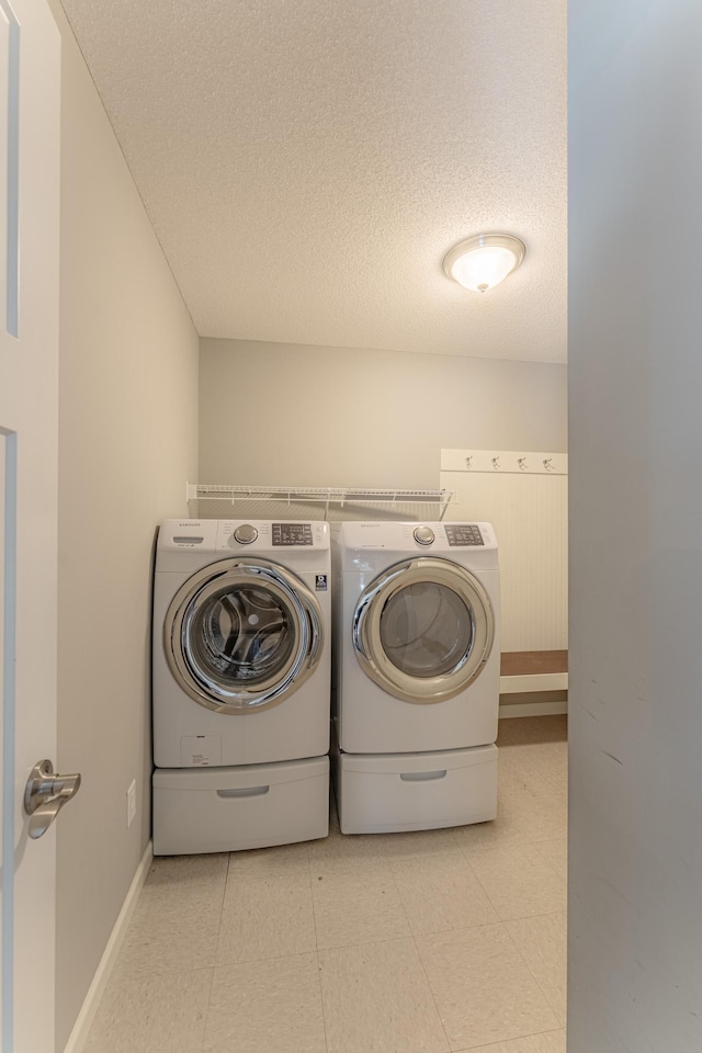 clothes washing area with a textured ceiling and washing machine and clothes dryer