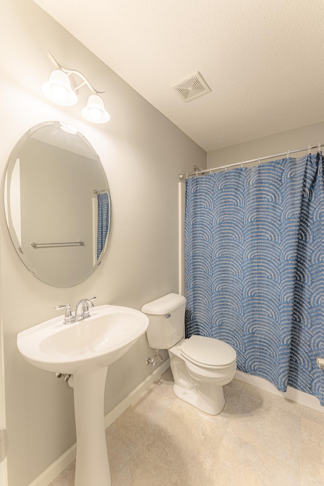 bathroom with toilet, a textured ceiling, and a shower with shower curtain