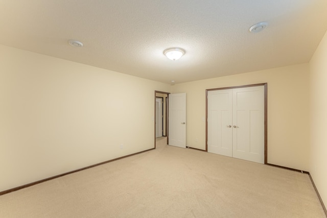 unfurnished bedroom featuring a closet, a textured ceiling, and light colored carpet