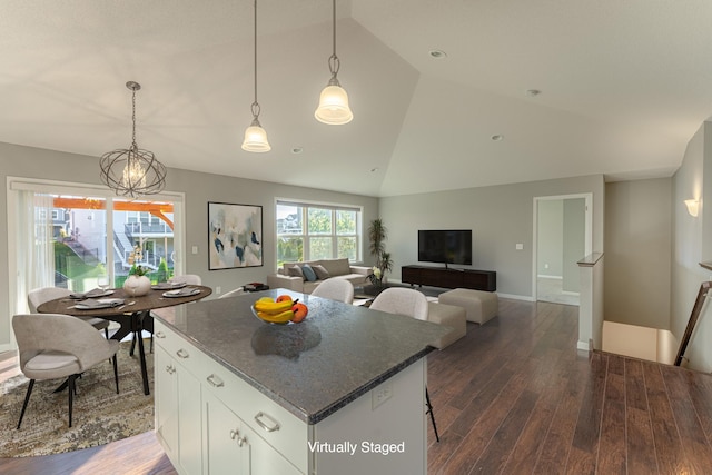 kitchen featuring lofted ceiling, a kitchen island, dark hardwood / wood-style flooring, white cabinetry, and dark stone countertops