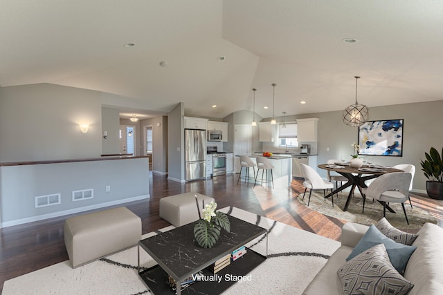 living room with vaulted ceiling, an inviting chandelier, and dark hardwood / wood-style flooring