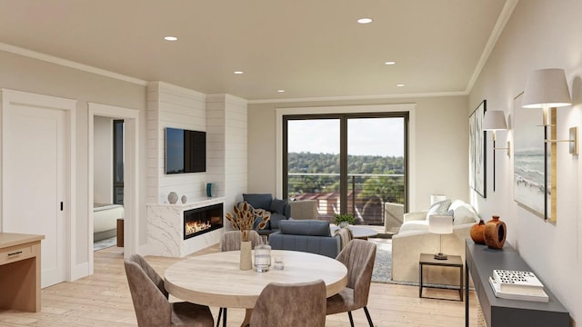 dining room with light hardwood / wood-style floors, crown molding, and a premium fireplace