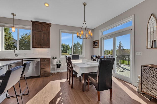 dining area featuring sink, light hardwood / wood-style floors, a chandelier, and a wealth of natural light