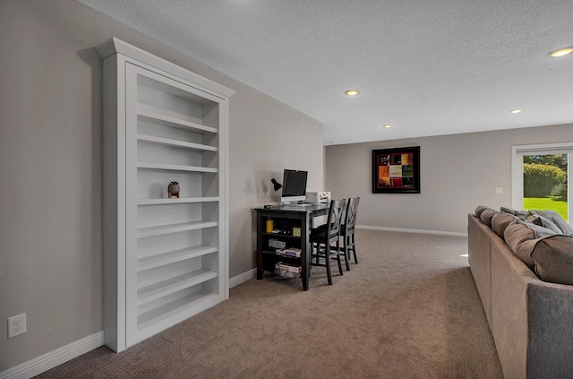 office area featuring a textured ceiling, built in shelves, and light colored carpet