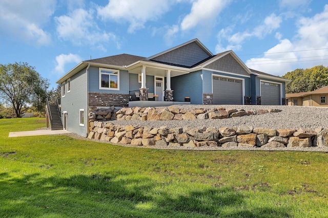 craftsman-style home with a garage, covered porch, and a front lawn