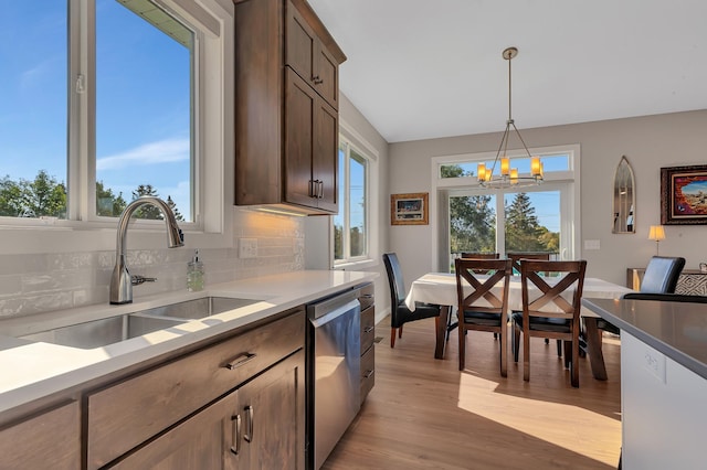 kitchen with hanging light fixtures, dark brown cabinets, sink, and stainless steel dishwasher