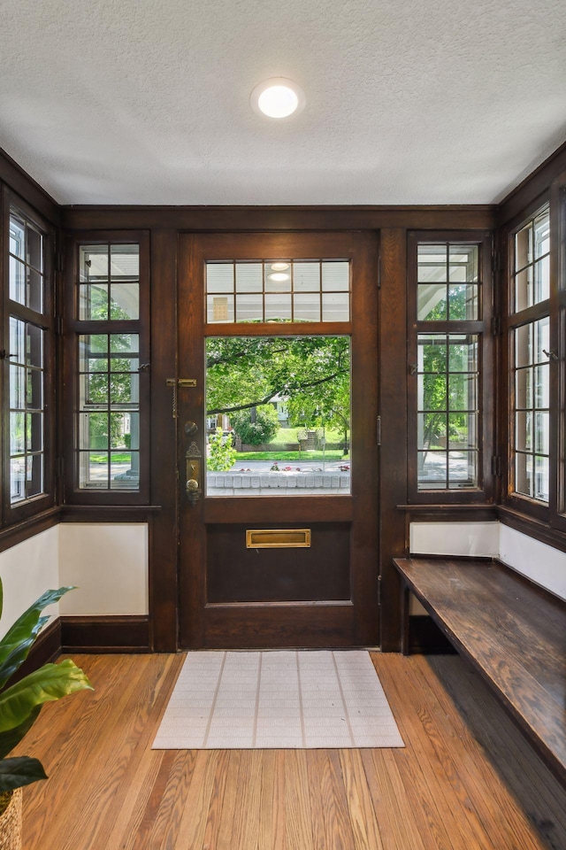 doorway to outside featuring a textured ceiling and light hardwood / wood-style floors