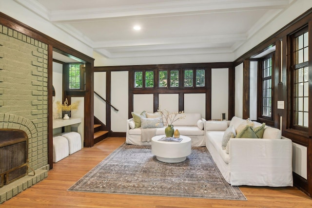 living room featuring light wood-type flooring, crown molding, and beam ceiling