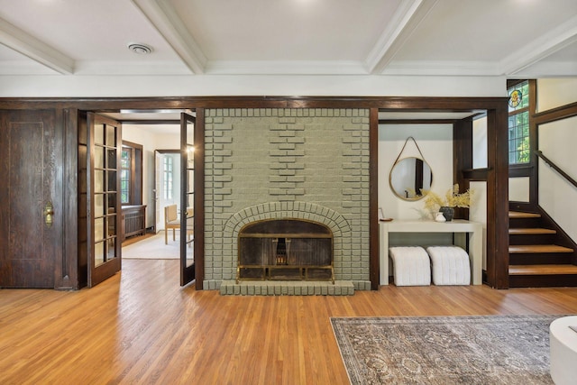 unfurnished living room featuring beamed ceiling, a brick fireplace, and hardwood / wood-style flooring