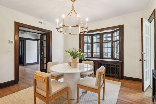 dining room featuring an inviting chandelier, crown molding, radiator, and hardwood / wood-style floors