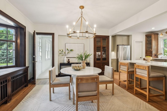 dining room with a notable chandelier, a wealth of natural light, and light wood-type flooring