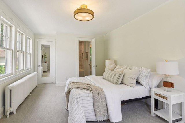 carpeted bedroom featuring radiator, ensuite bath, and multiple windows