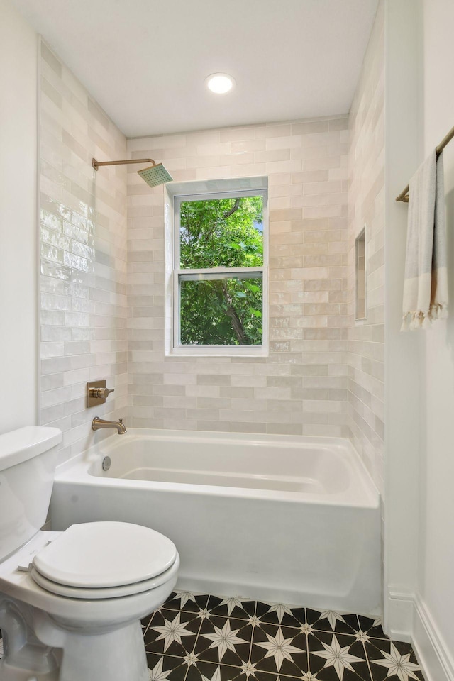 bathroom with tiled shower / bath combo and toilet