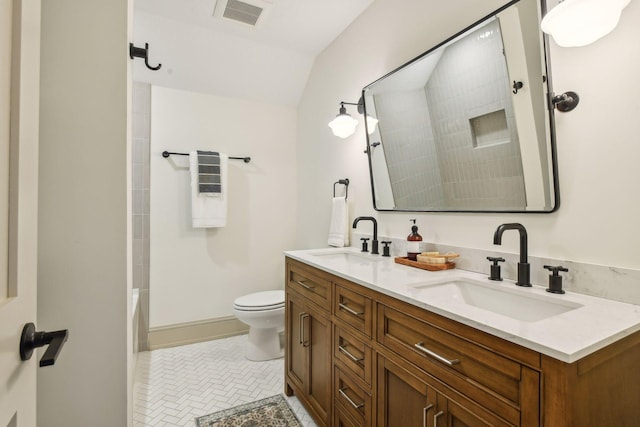 bathroom with tile patterned flooring, vanity, toilet, and vaulted ceiling