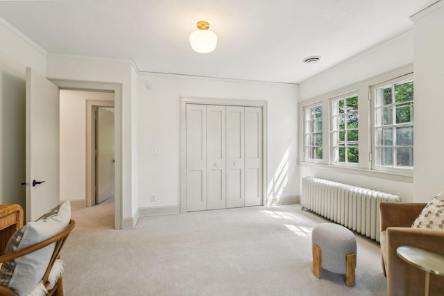 sitting room with light carpet, radiator, and crown molding