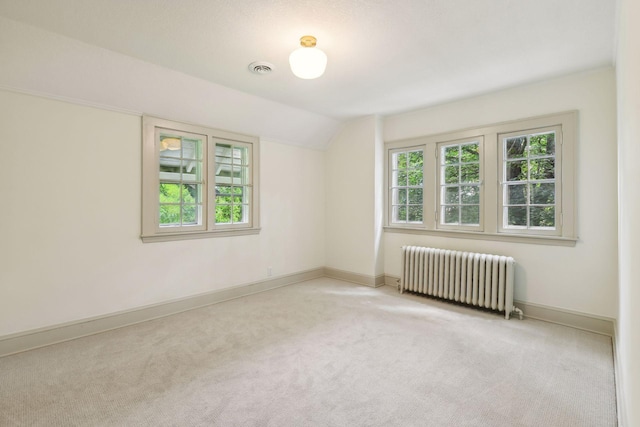 unfurnished room with light colored carpet, vaulted ceiling, and radiator heating unit