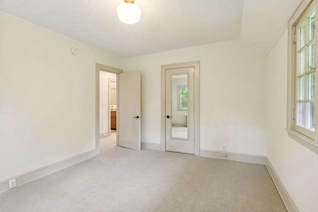 carpeted spare room with ornamental molding, vaulted ceiling, and a wealth of natural light