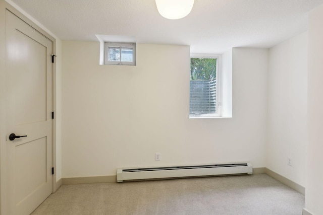 unfurnished room with light colored carpet, a textured ceiling, a baseboard heating unit, and a wealth of natural light