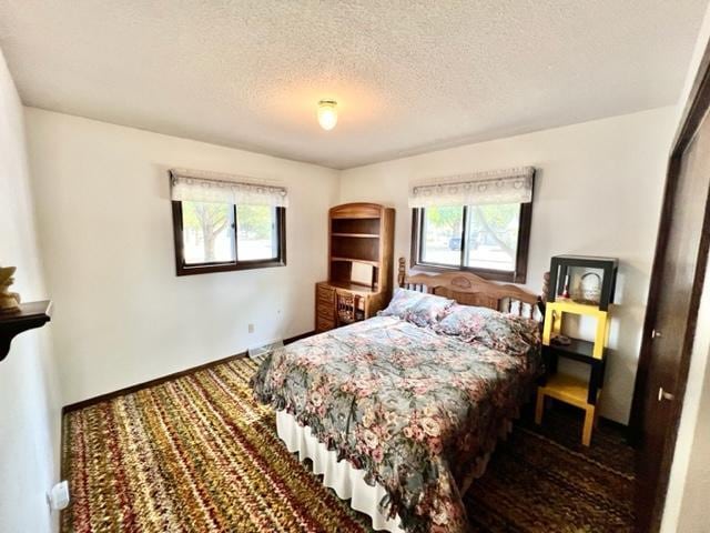 bedroom with a textured ceiling and multiple windows