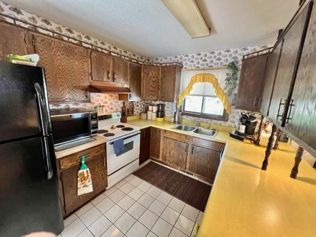 kitchen with light tile patterned floors, black refrigerator, a textured ceiling, white range with electric cooktop, and sink